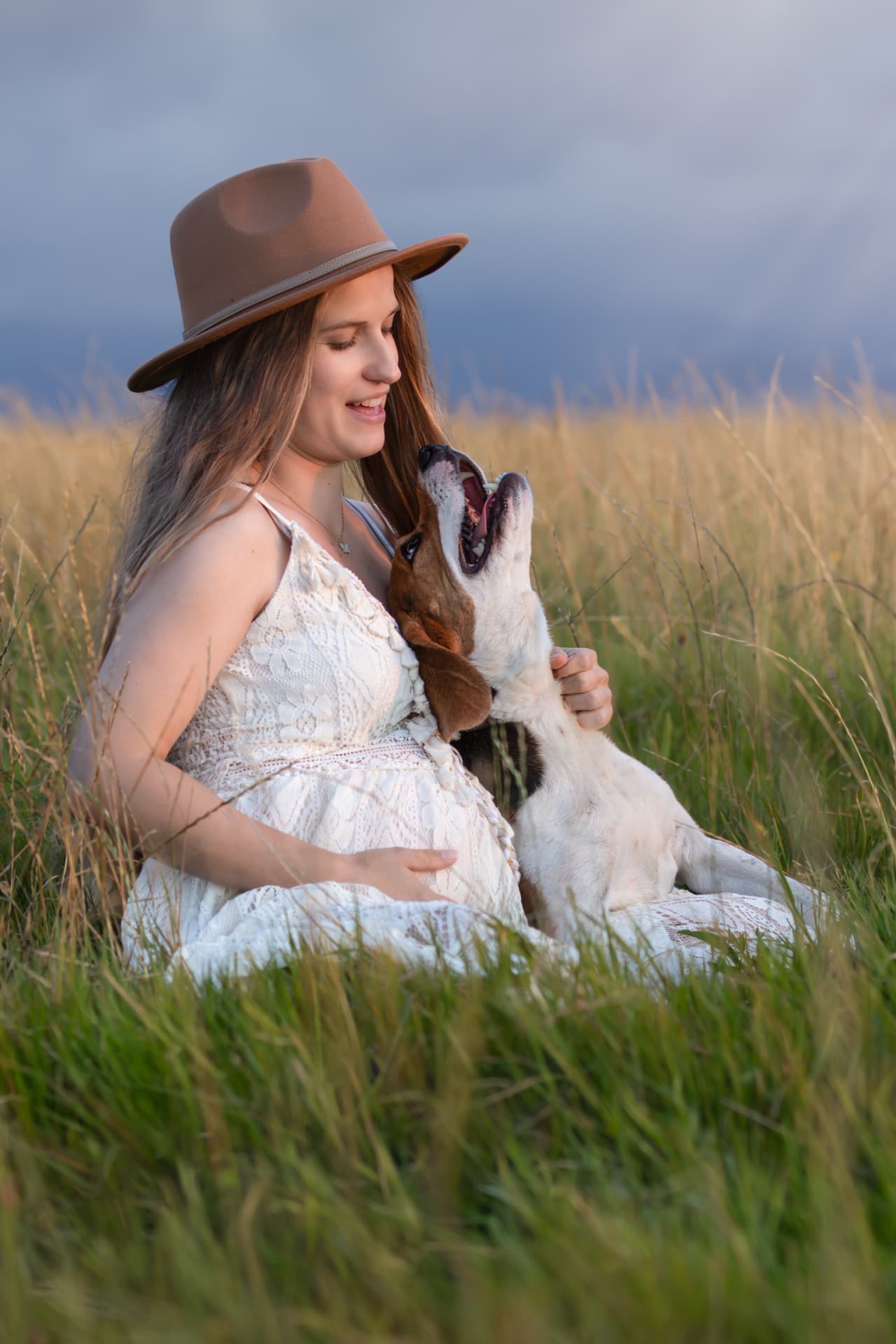 Séance photo grossesse avec animal : ventre rond et chien de famille, en prairie